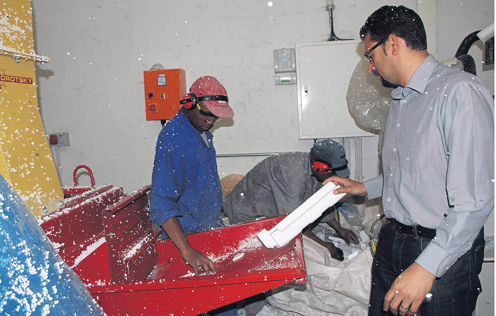 Noel Ehrenreich demonstrates how polystyrene is fed into the machine.
